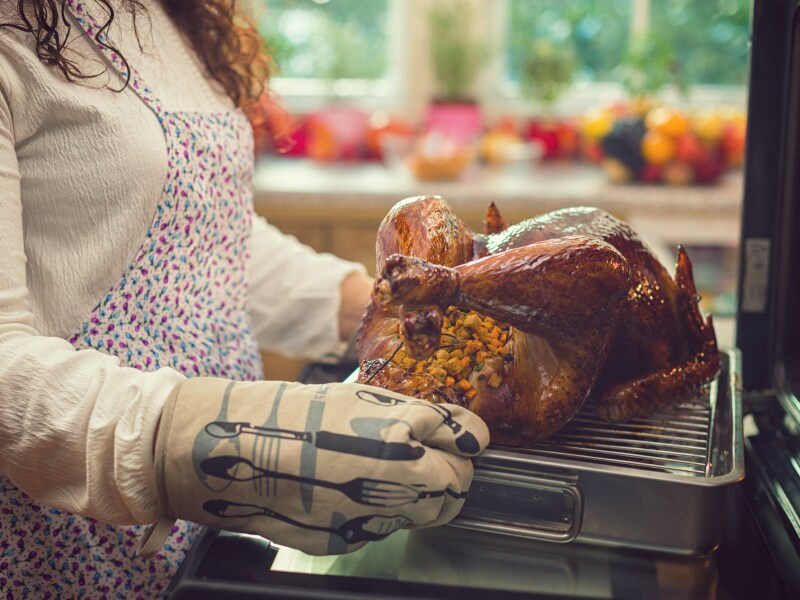  A person pulling a turkey out of a KitchenAid® wall oven