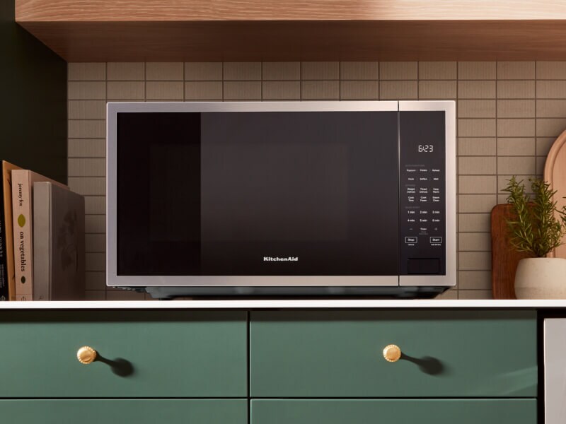 KitchenAid® countertop microwave above green cabinetry 