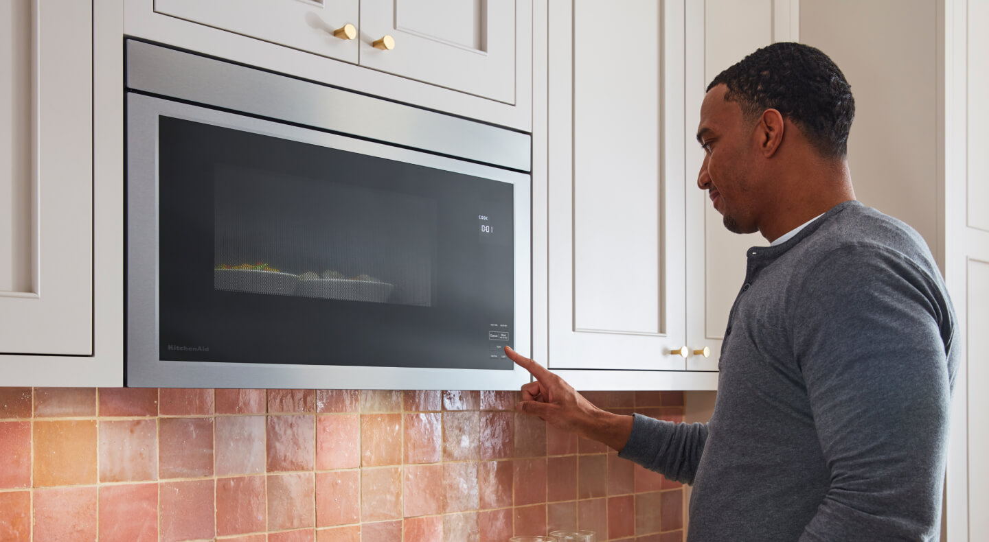 Person selecting settings on a KitchenAid® over-the-range microwave
