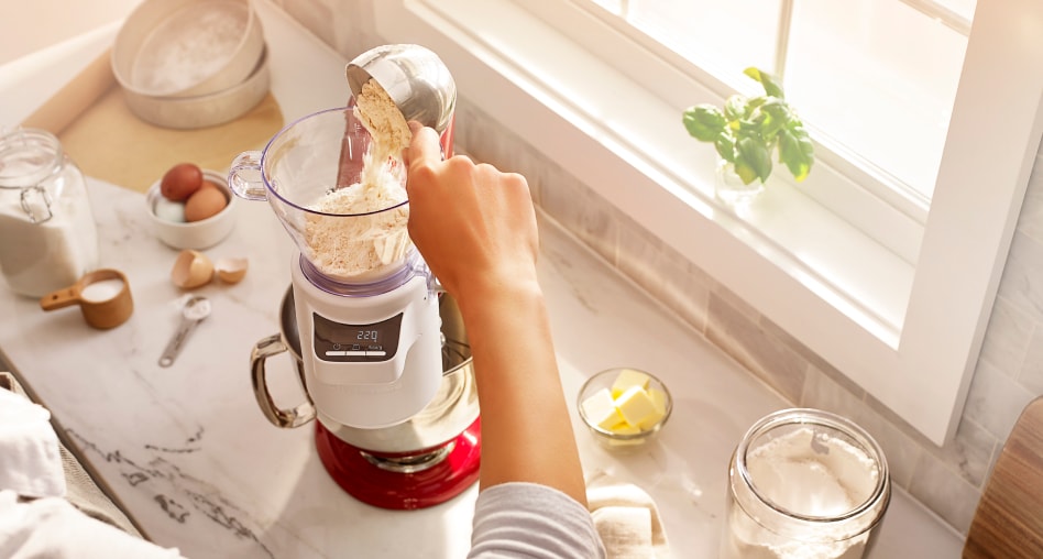 Hand pouring flour into a stand mixer with a sifting attachment Hand pouring flour into a stand mixer with a sifting attachment