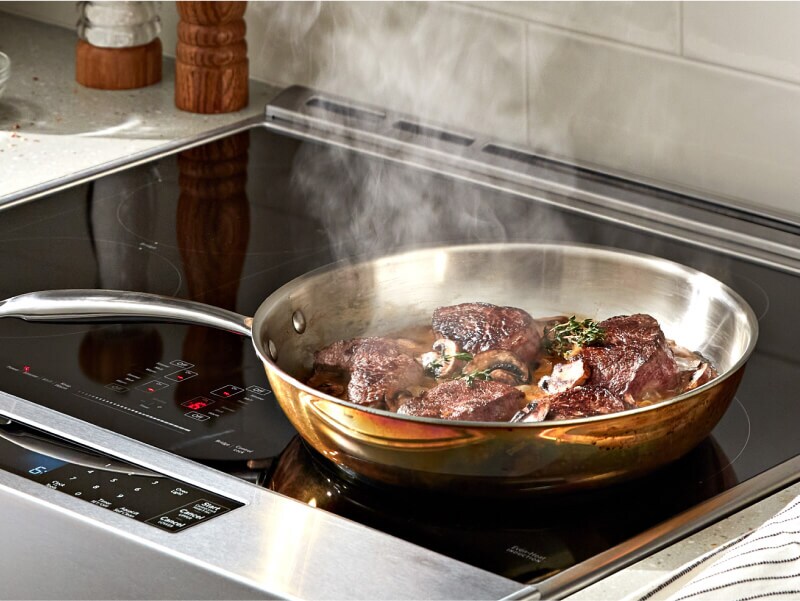 Ribeye steak cooking on a KitchenAid® cooktop