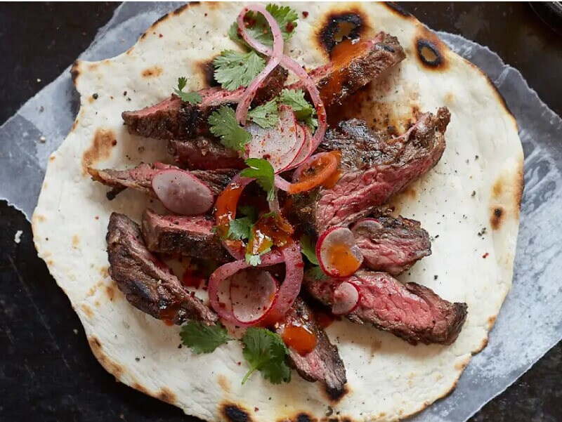 Skirt steak inside a tortilla with pickled onions