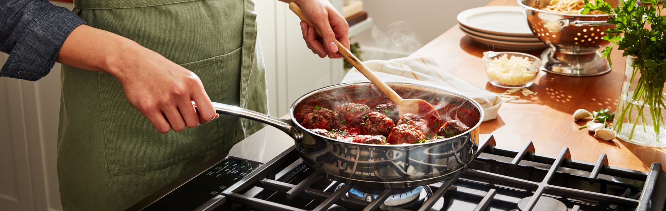 A person preparing food in a pan on a gas cooktop