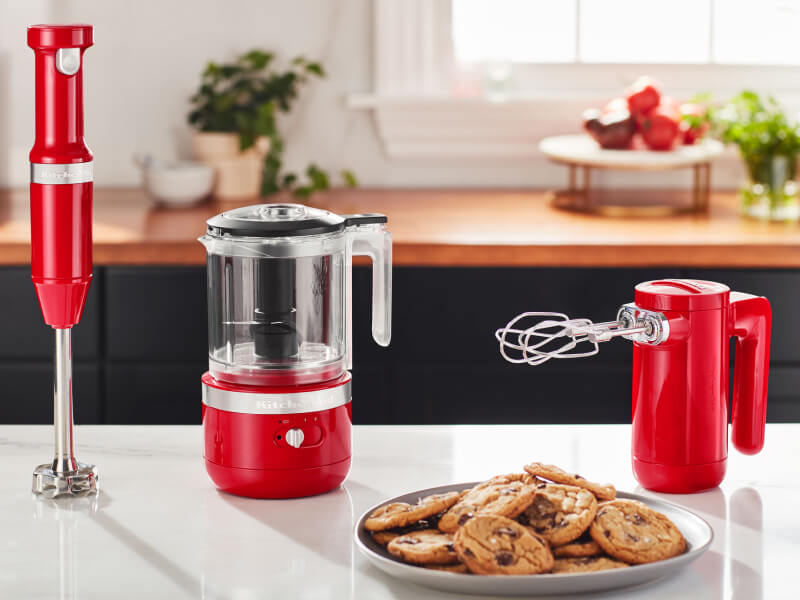 KitchenAid® red cordless hand blender, food chopper and hand mixer on a countertop KitchenAid® red cordless hand blender, food chopper and hand mixer on a countertop