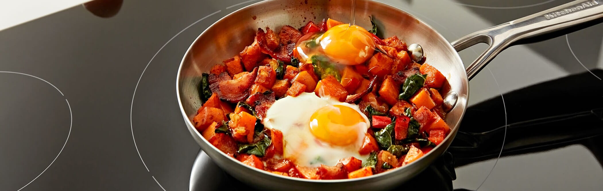 Eggs and veggies cooking in a pan on a stovetop