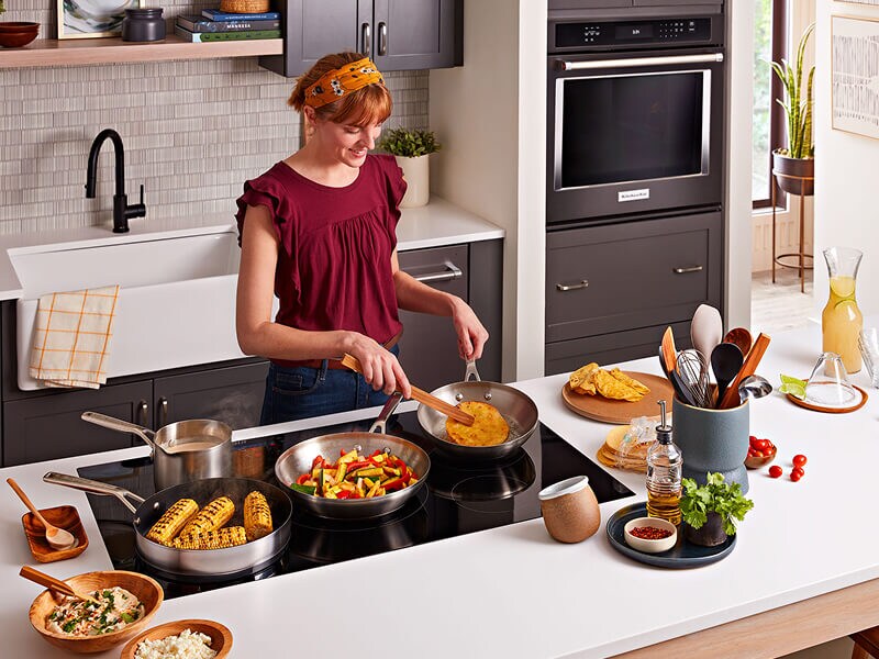 A woman cooking several dishes at her induction cooktop