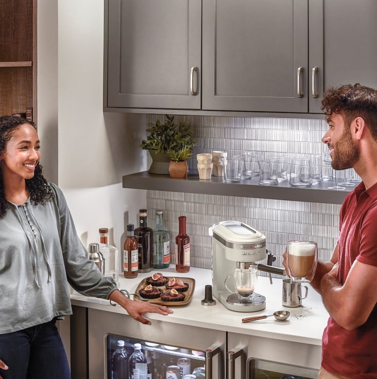 Couple chatting next to bar with espresso maker and undercounter refrigeration
