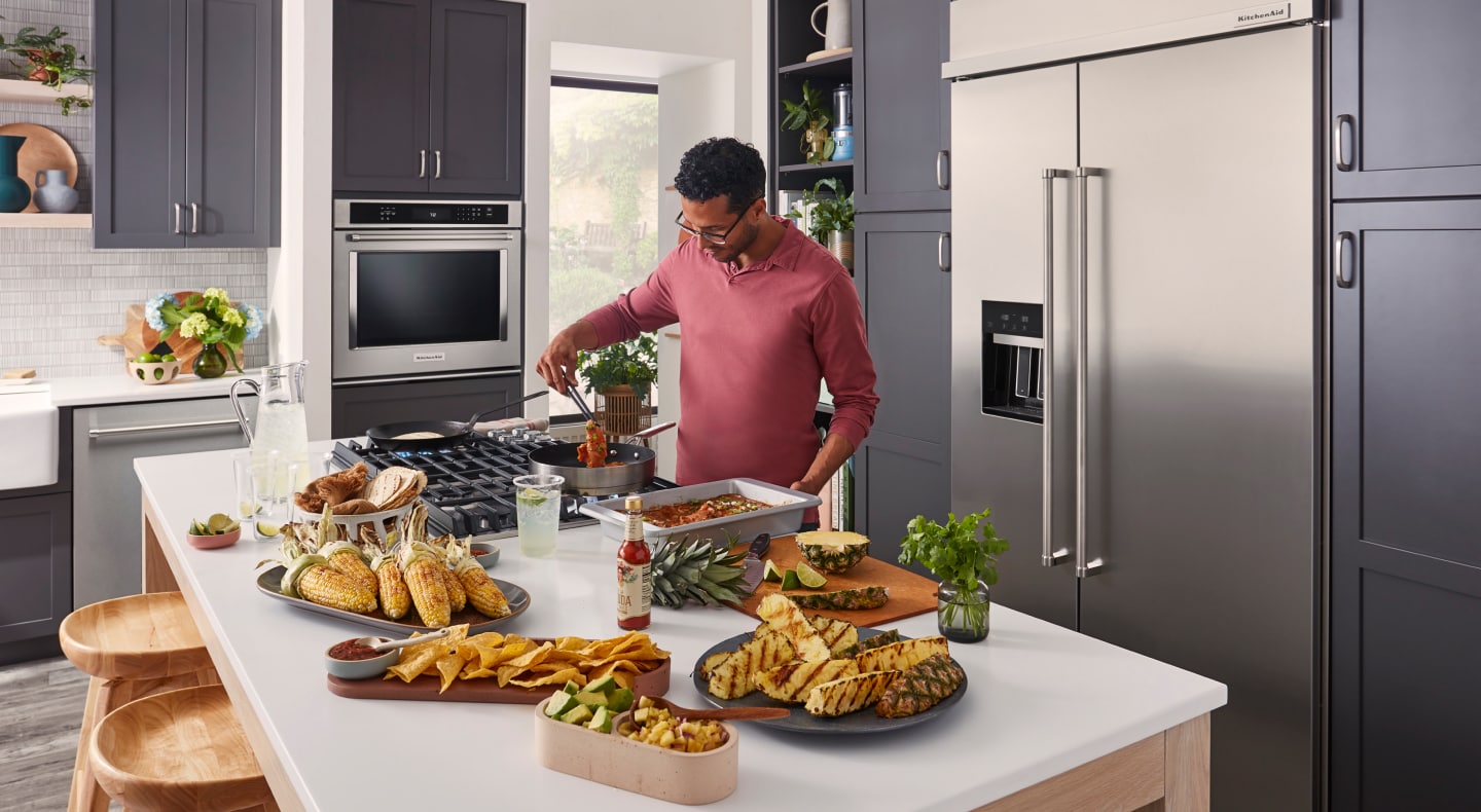 Man cooking chicken on kitchen island cooktop