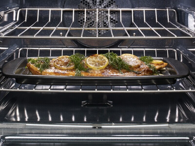 Fish with garnishes in a pan in the oven