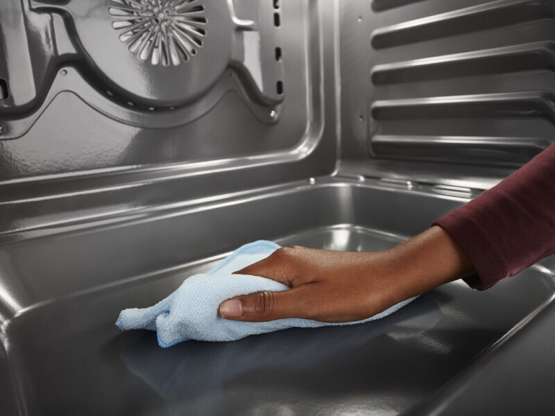 Person wiping down the inside of an oven