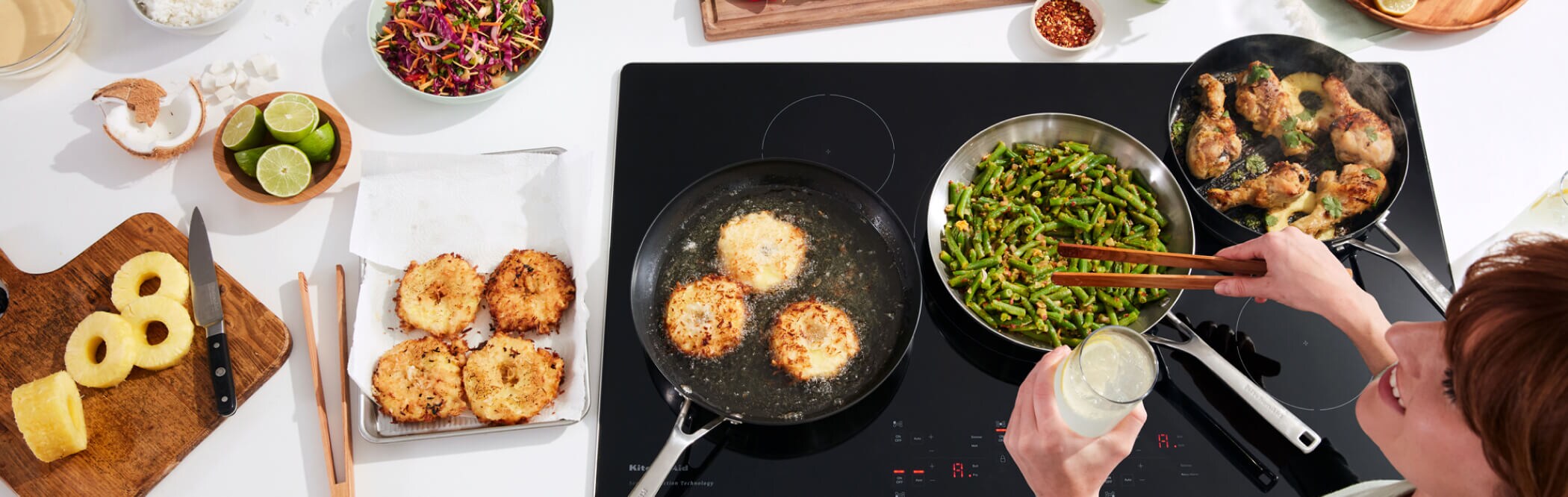 A person preparing various types of food on a KitchenAid® Cooktop