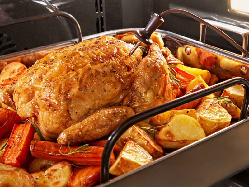 A close up of chicken and vegetables roasting in an oven