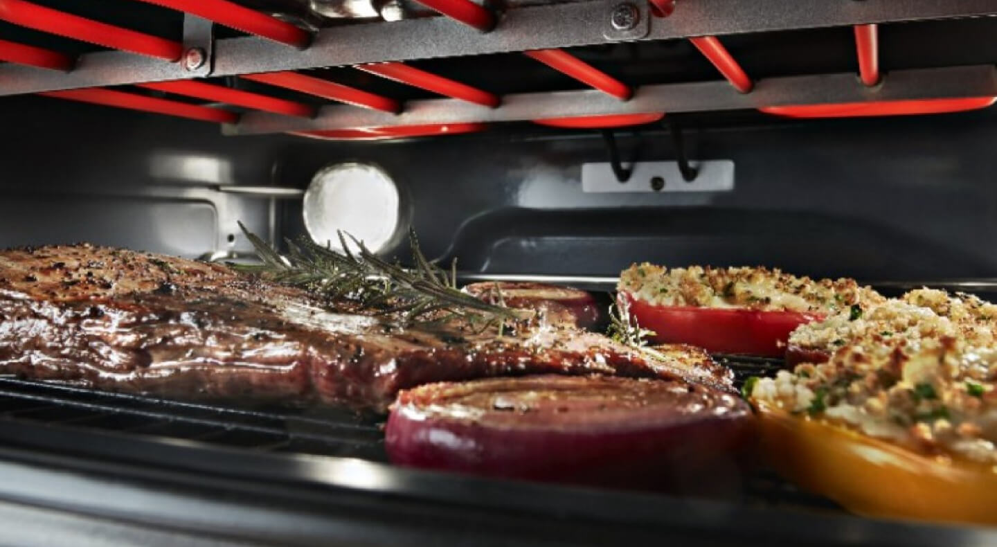 Close up image of meat and vegetables broiling in an oven
