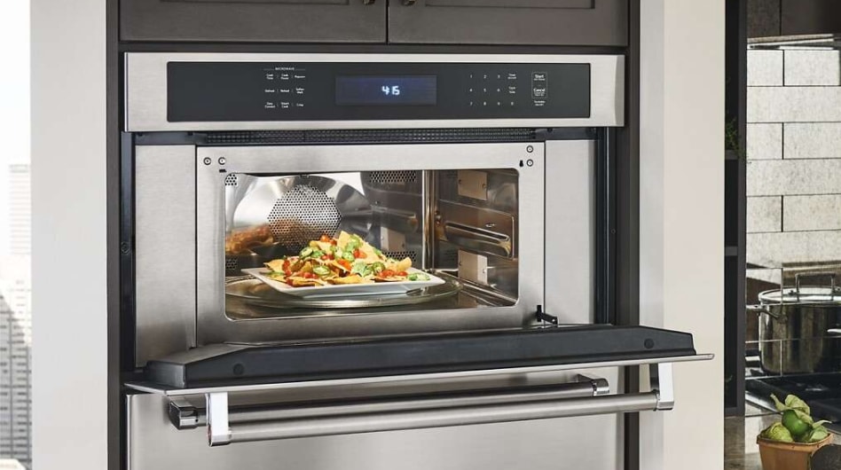 An open KitchenAid® built-in microwave with nachos inside An open KitchenAid® built-in microwave with nachos inside