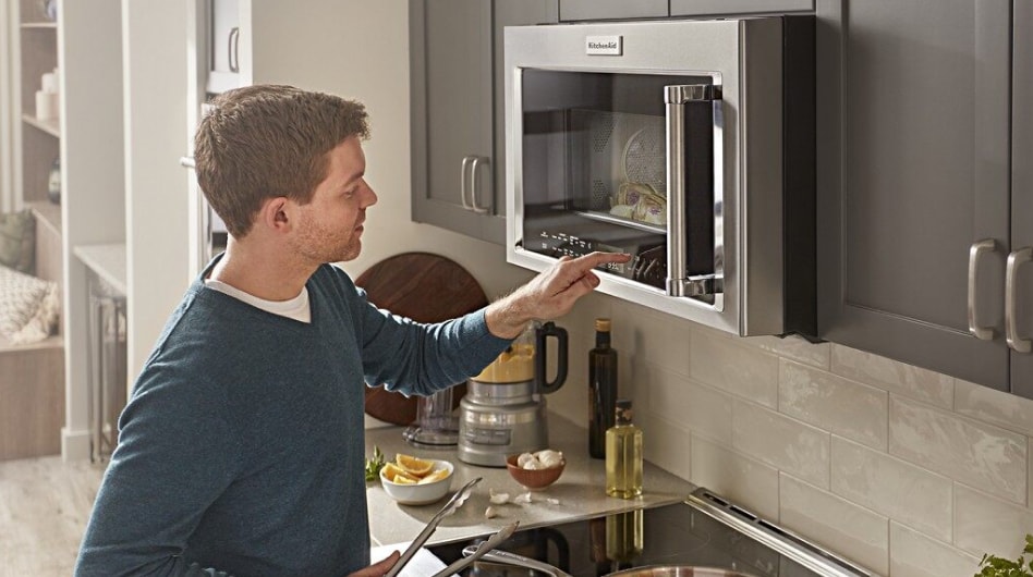 A person pressing the controls on a KitchenAid® microwave A person pressing the controls on a KitchenAid® microwave