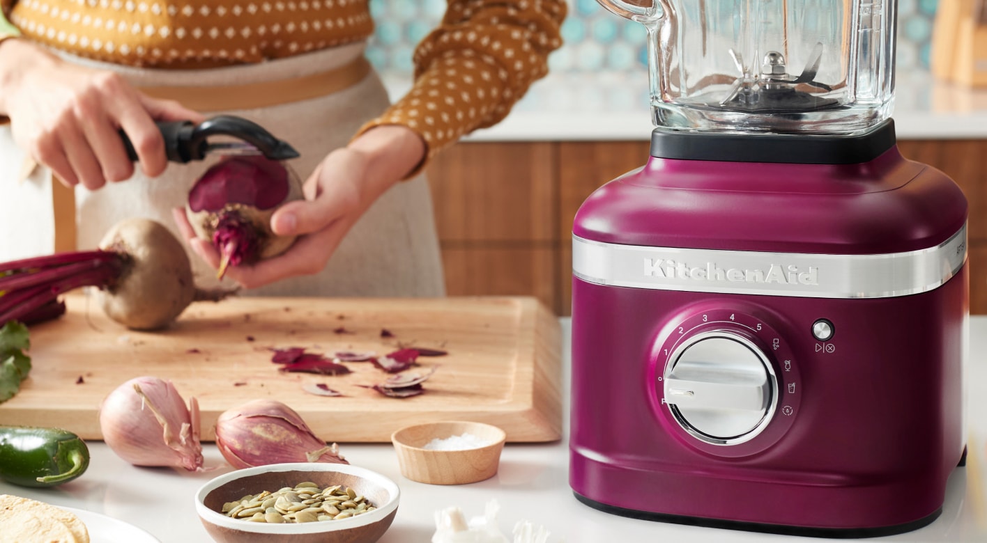 KitchenAid® blender in Beetroot on countertop next to woman preparing beets KitchenAid® blender in Beetroot on countertop next to woman preparing beets