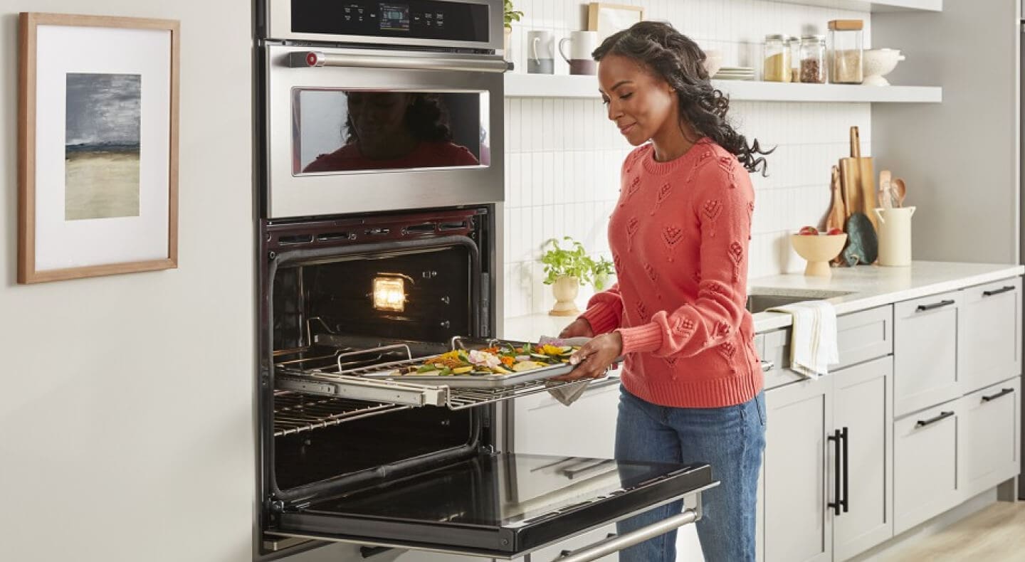 A woman using a KitchenAid® combination oven to roast vegetables A woman using a KitchenAid® combination oven to roast vegetables
