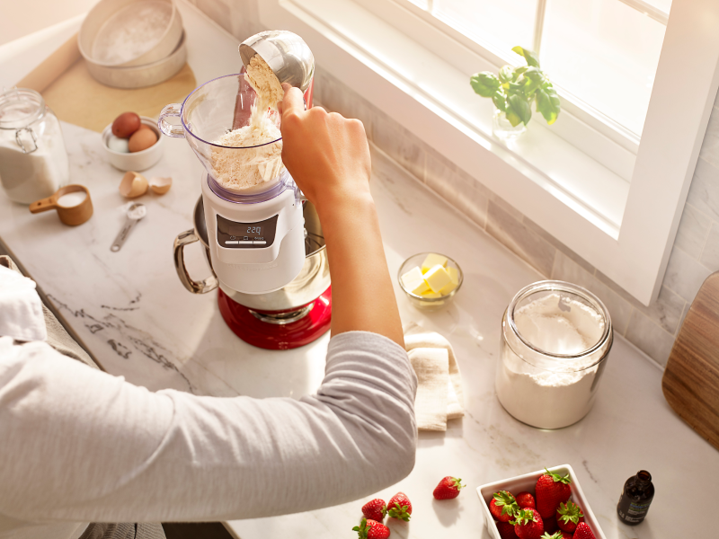 A person pouring flour into KitchenAid® Sifter & Scale Attachment. A person pouring flour into KitchenAid® Sifter & Scale Attachment.