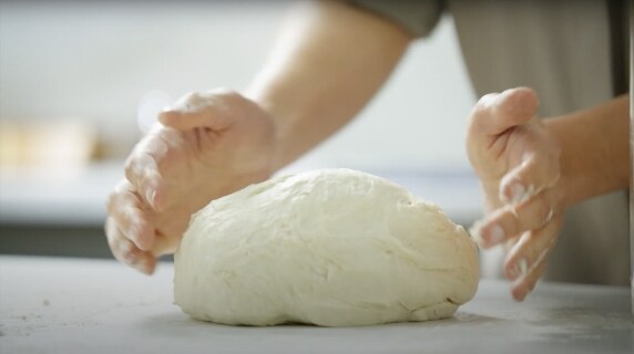 A person forming a mound of dough.