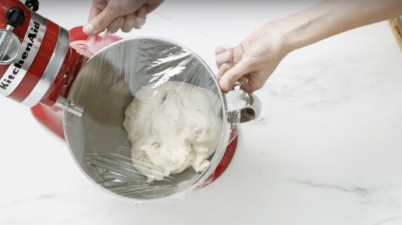 A stand mixer bowl being covered with cling film.