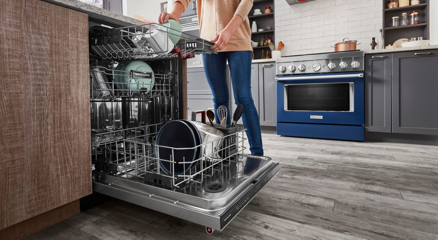 Woman loading dishes in a three rack dishwasher Woman loading dishes in a three rack dishwasher
