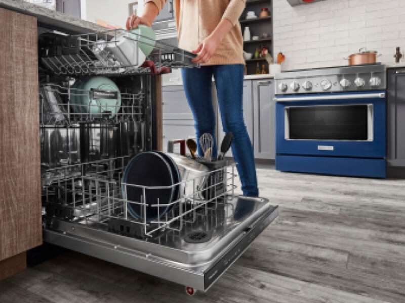 Woman loading dishes in a three rack dishwasher Woman loading dishes in a three rack dishwasher
