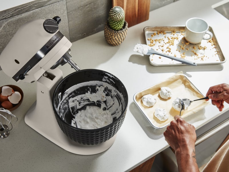 Person putting dough onto prepared baking dish