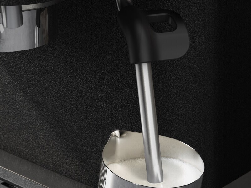 Espresso machine steam wand inside a milk carafe