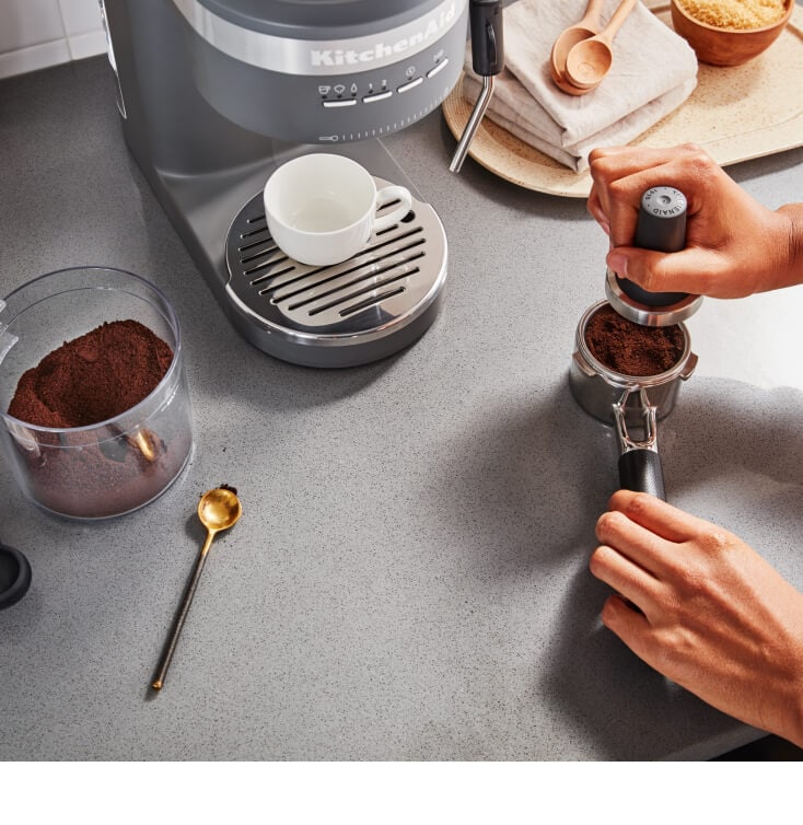 Person tamping coffee in an espresso machine portafilter