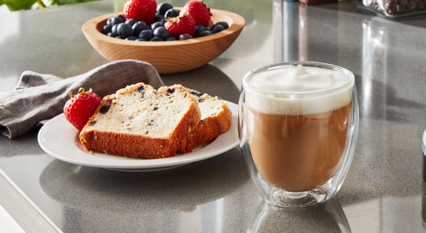 Espresso drink on counter with slices of bread and fruit Espresso drink on counter with slices of bread and fruit