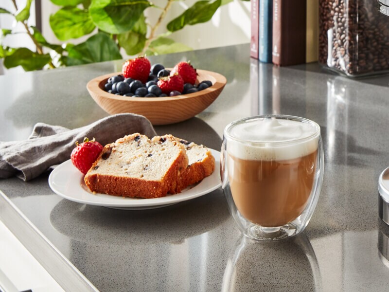 Espresso drink on counter with slices of bread and fruit Espresso drink on counter with slices of bread and fruit