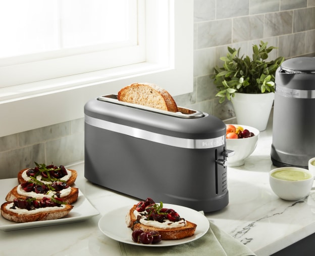 Toaster on a kitchen counter next to toast with fruit preserves