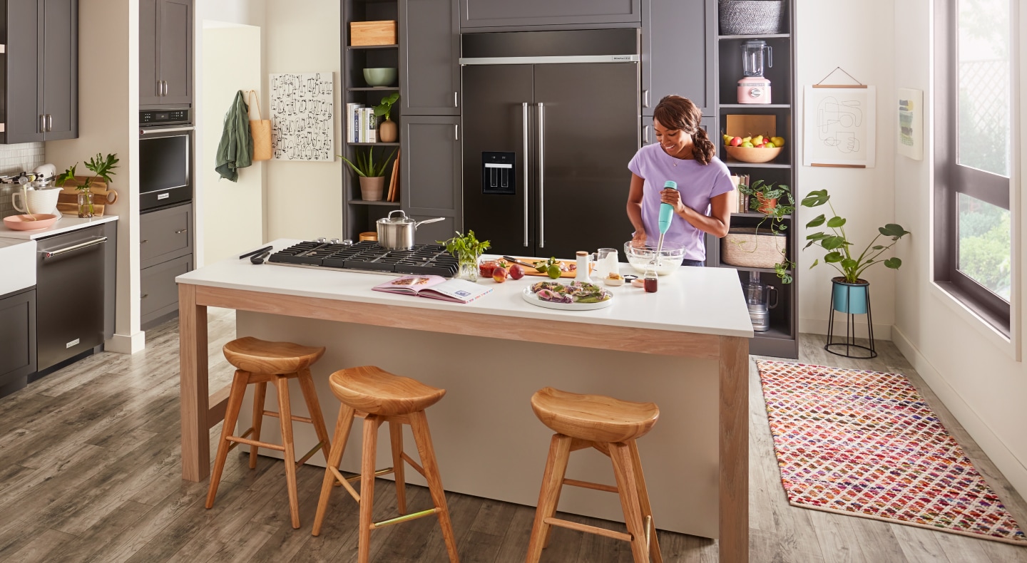A woman using an immersion blender in a kitchen A woman using an immersion blender in a kitchen