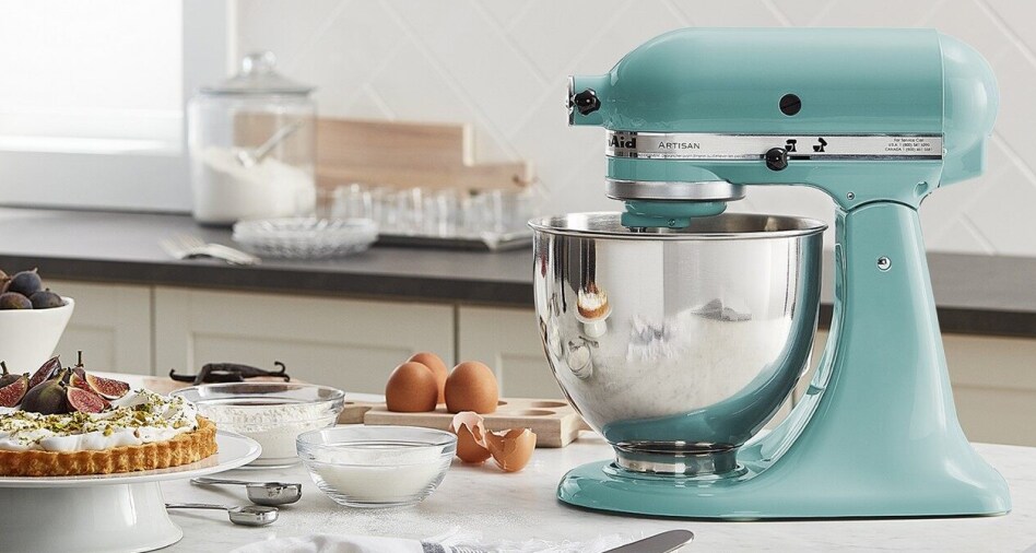 Blue KitchenAid brand stand mixer next to eggs, spices and a baked tart Blue KitchenAid brand stand mixer next to eggs, spices and a baked tart