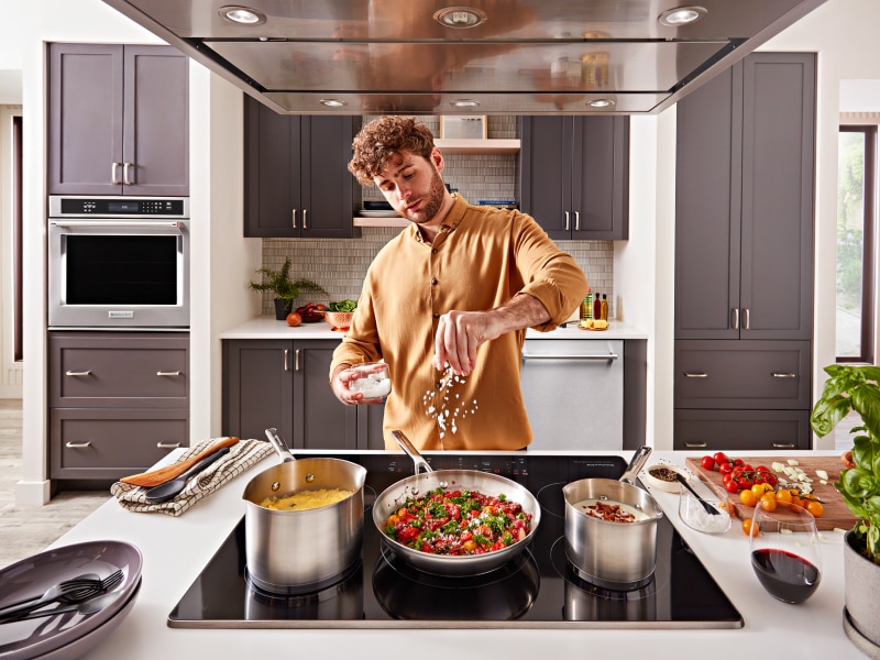 Person adding seasoning to a pan Person adding seasoning to a pan