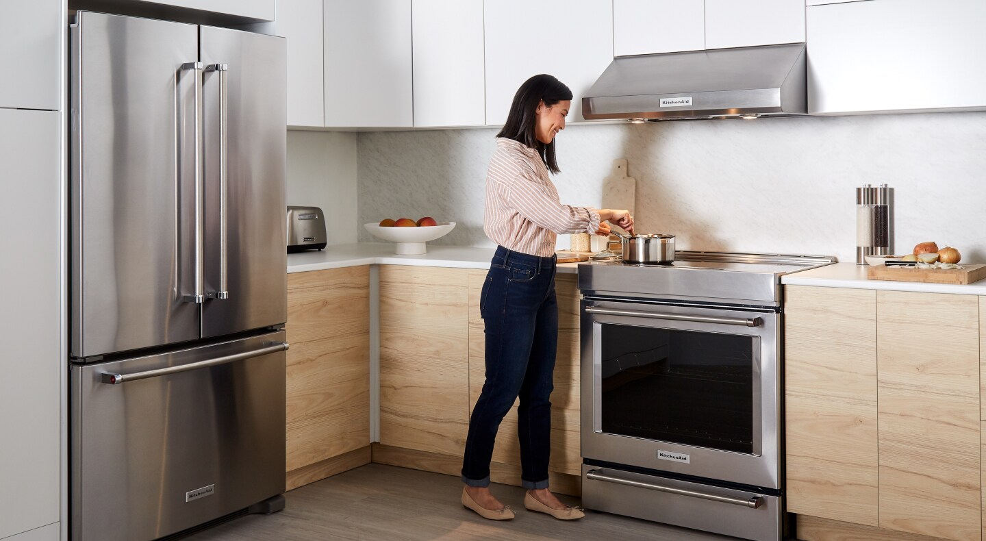 KitchenAid® French door refrigerator, electric range and range hood in white and light brown cabinets