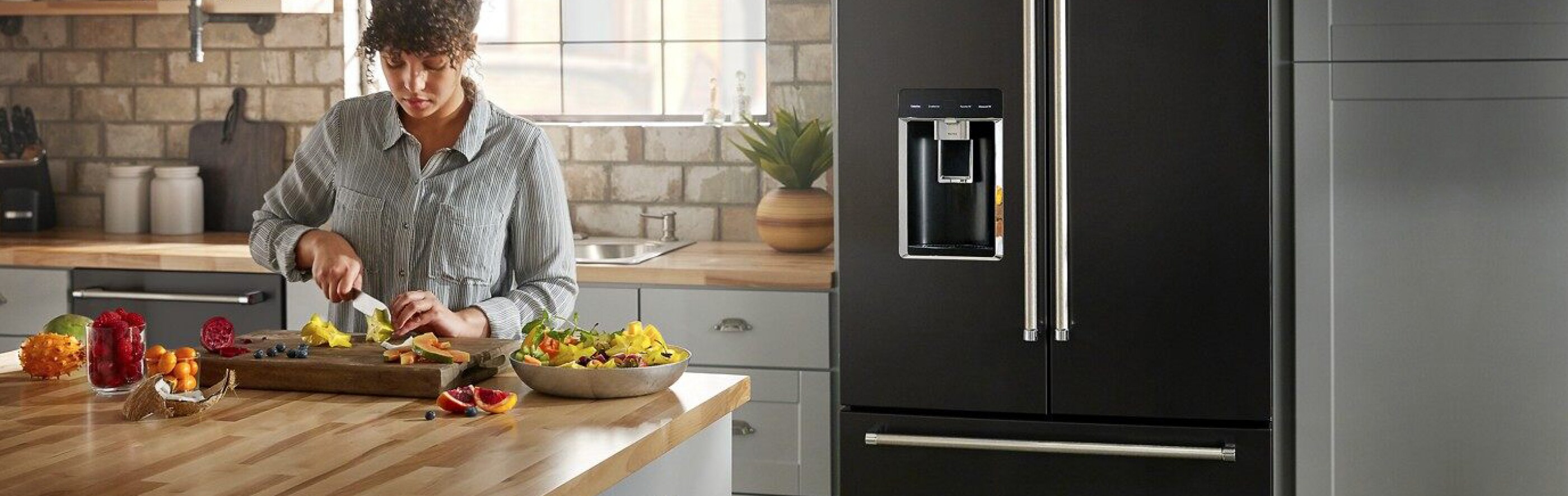 Woman chopping fruit in front of a French door refrigerator