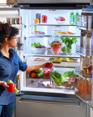 Person loading produce inside a French door refrigerator