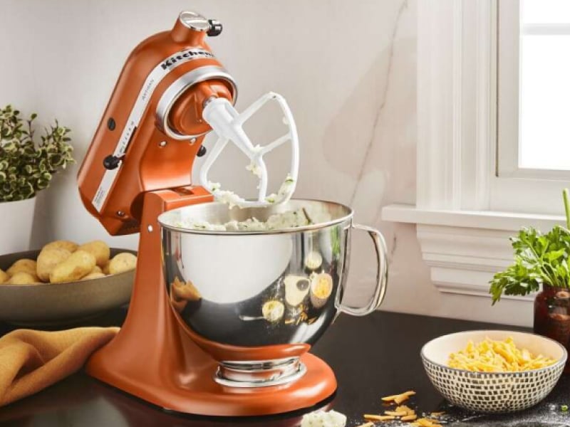Orange KitchenAid® stand mixer with flat beater whipping mashed potatoes