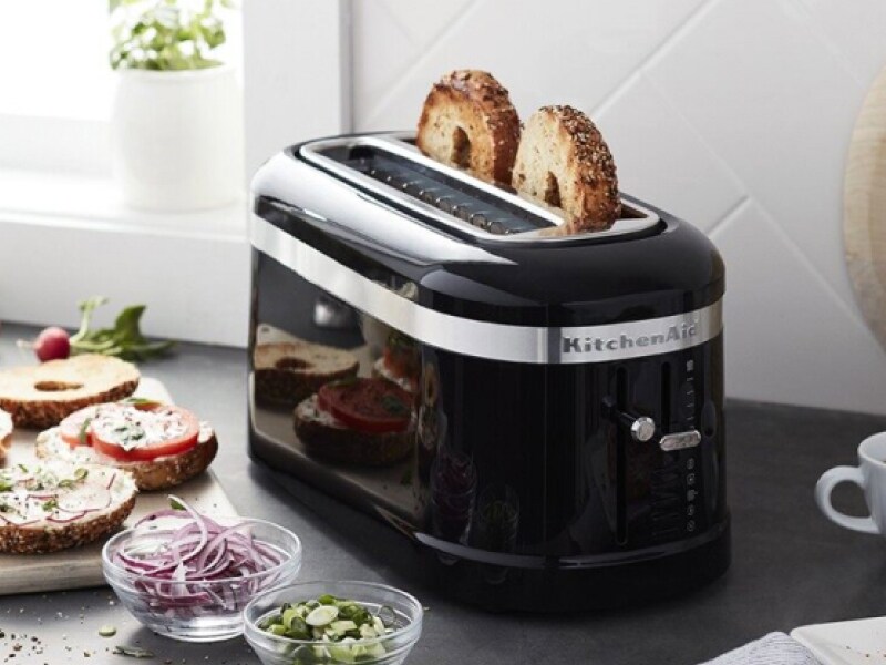 Black KitchenAid® toaster with two bagels inside sitting on counter with ingredients