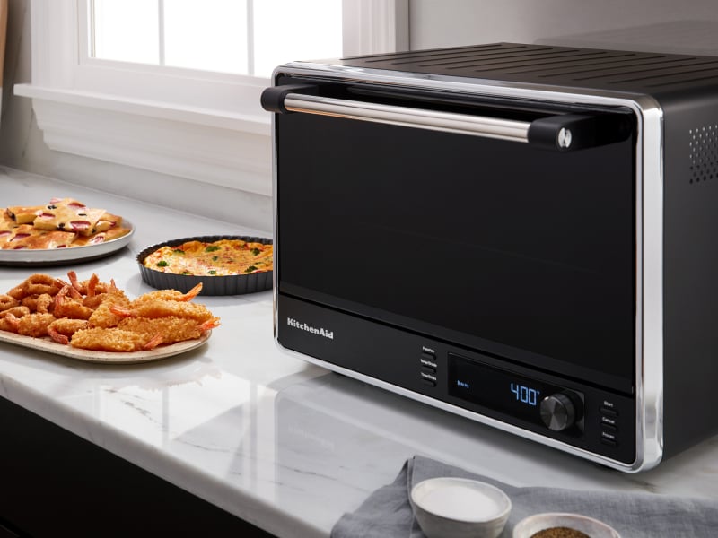 Black and silver KitchenAid® countertop oven on counter with food