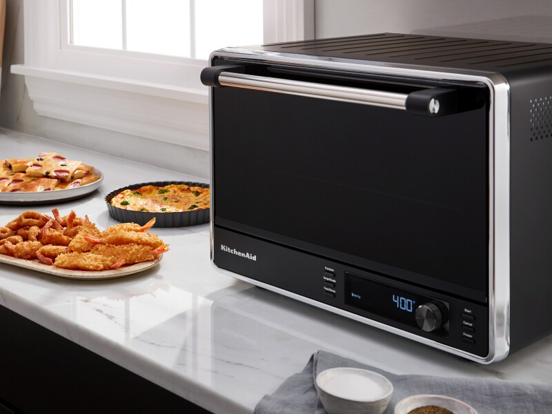 Black and silver KitchenAid® countertop oven on counter with food