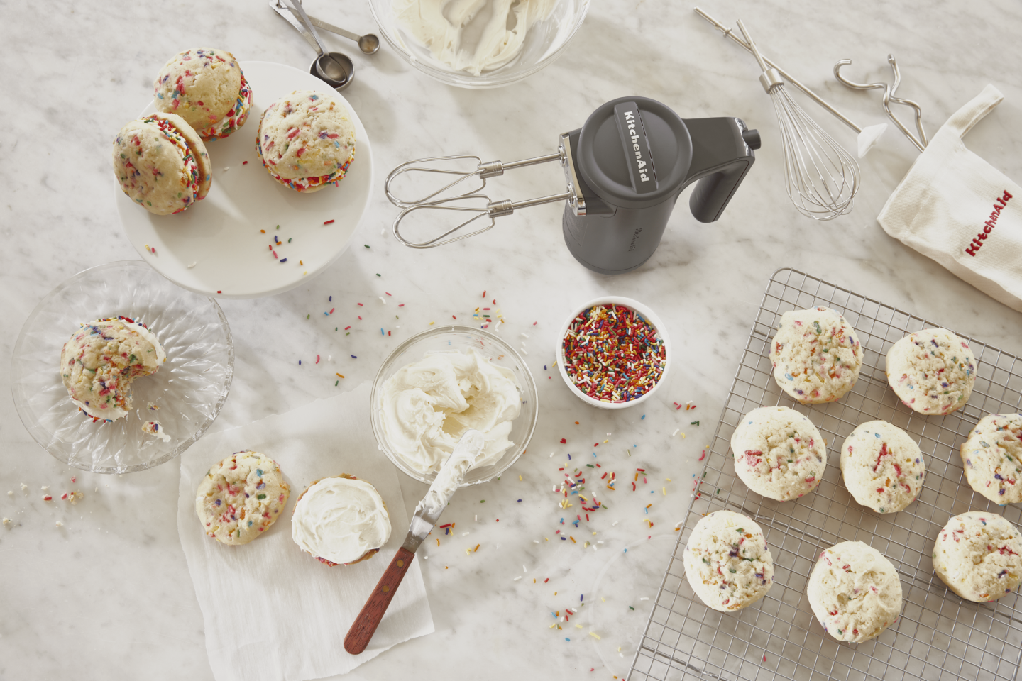 Gray KitchenAid® hand mixer standing upright on countertop along with sandwich cookies, frosting, sprinkles and beater accessories Gray KitchenAid® hand mixer standing upright on countertop along with sandwich cookies, frosting, sprinkles and beater accessories