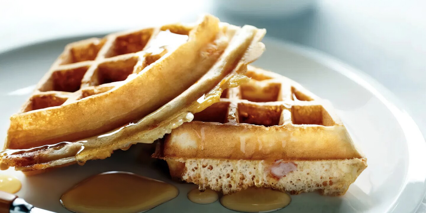 Two quarters of waffles sitting on a plate, drizzled with syrup. Two quarters of waffles sitting on a plate, drizzled with syrup.