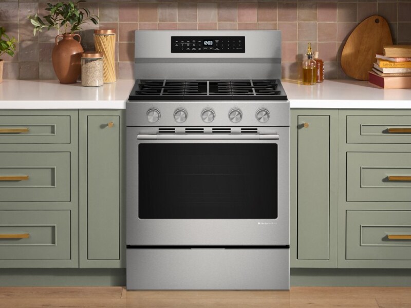 A gas range in a bright kitchen with white countertops