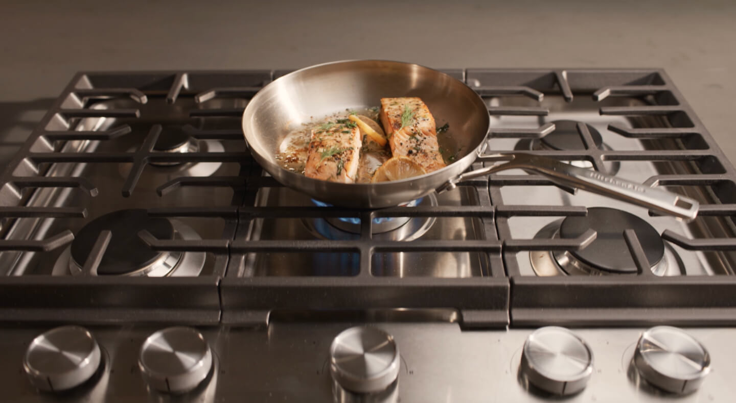Food cooking in a pan on a gas cooktop