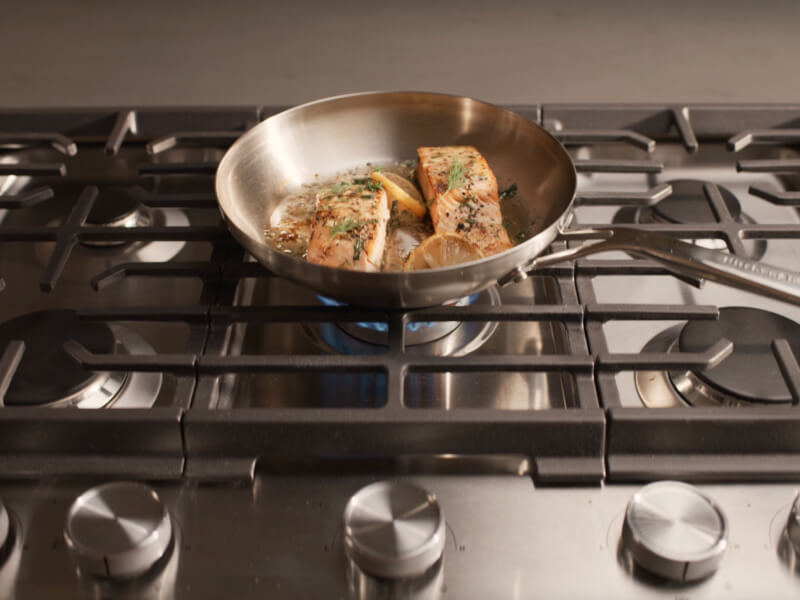 Food cooking in a pan on a gas cooktop