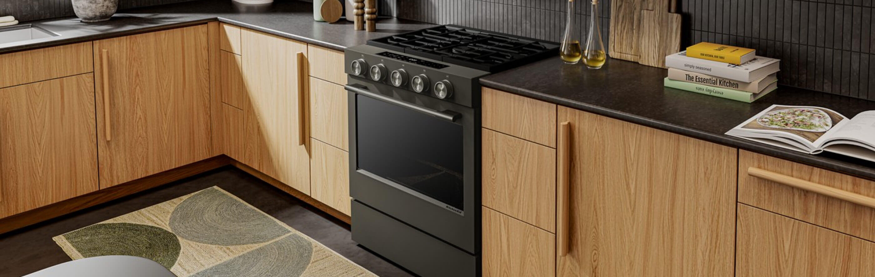 A kitchen with a warm feel, gas stove, and dark countertops