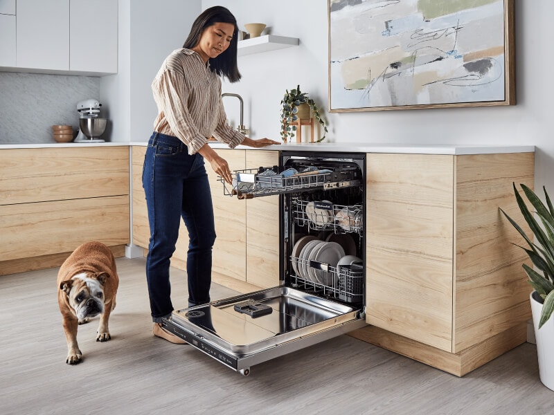 Person loading the third rack of a panel-ready dishwasher  Person loading the third rack of a panel-ready dishwasher