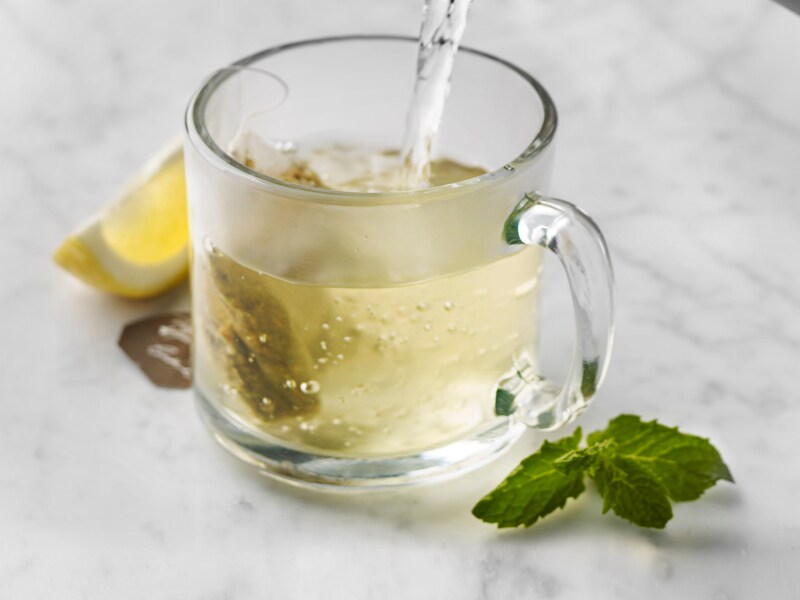 Glass mug of green tea with mint and lemon